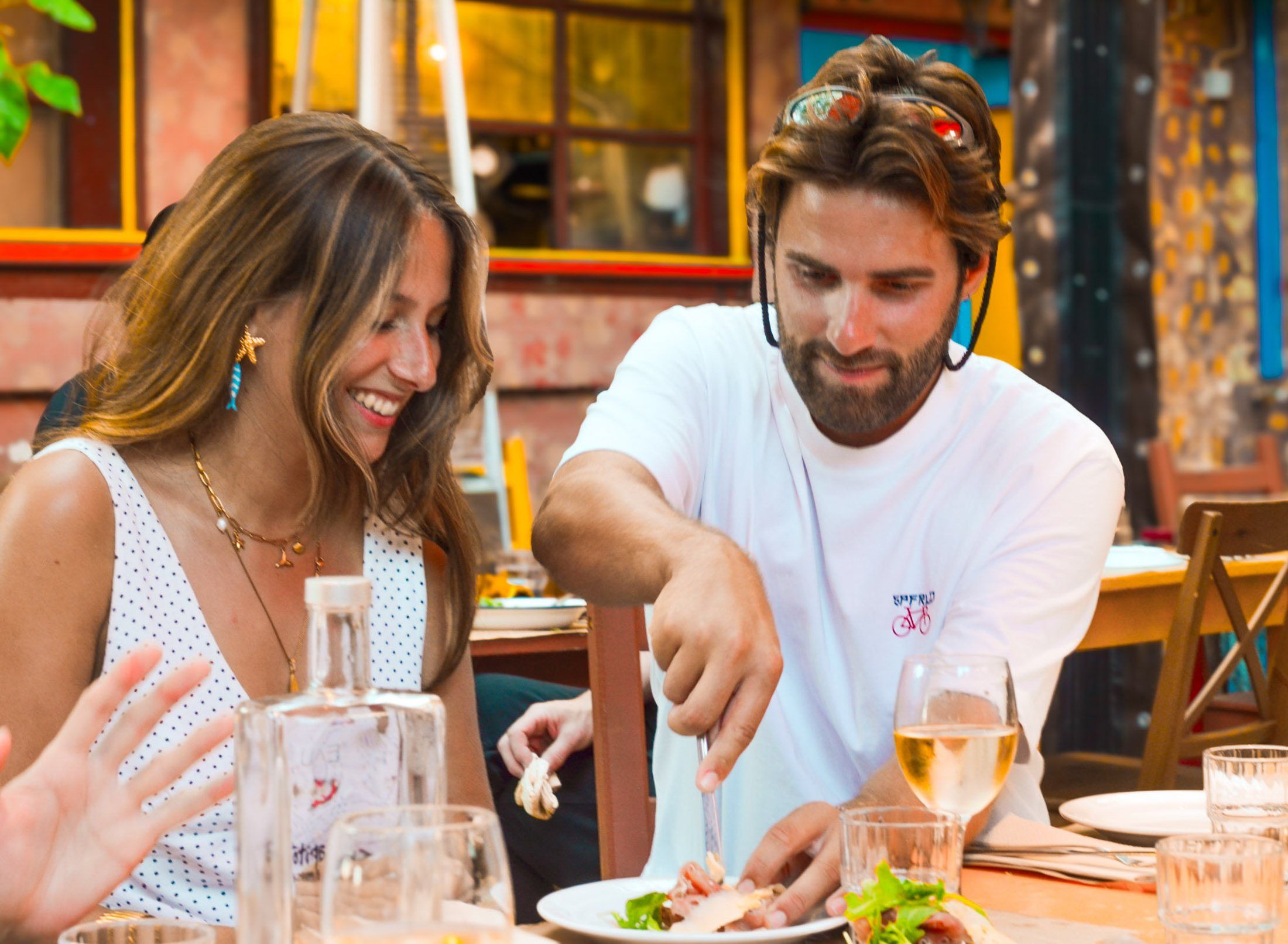 Two guests sharing cured meats and wine at an outdoor table