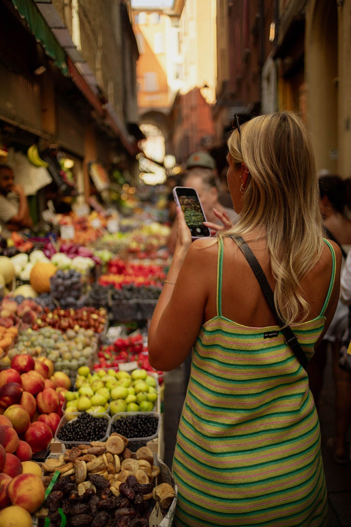 A guest photographing fruit stalls in the Quadrilatero market streets