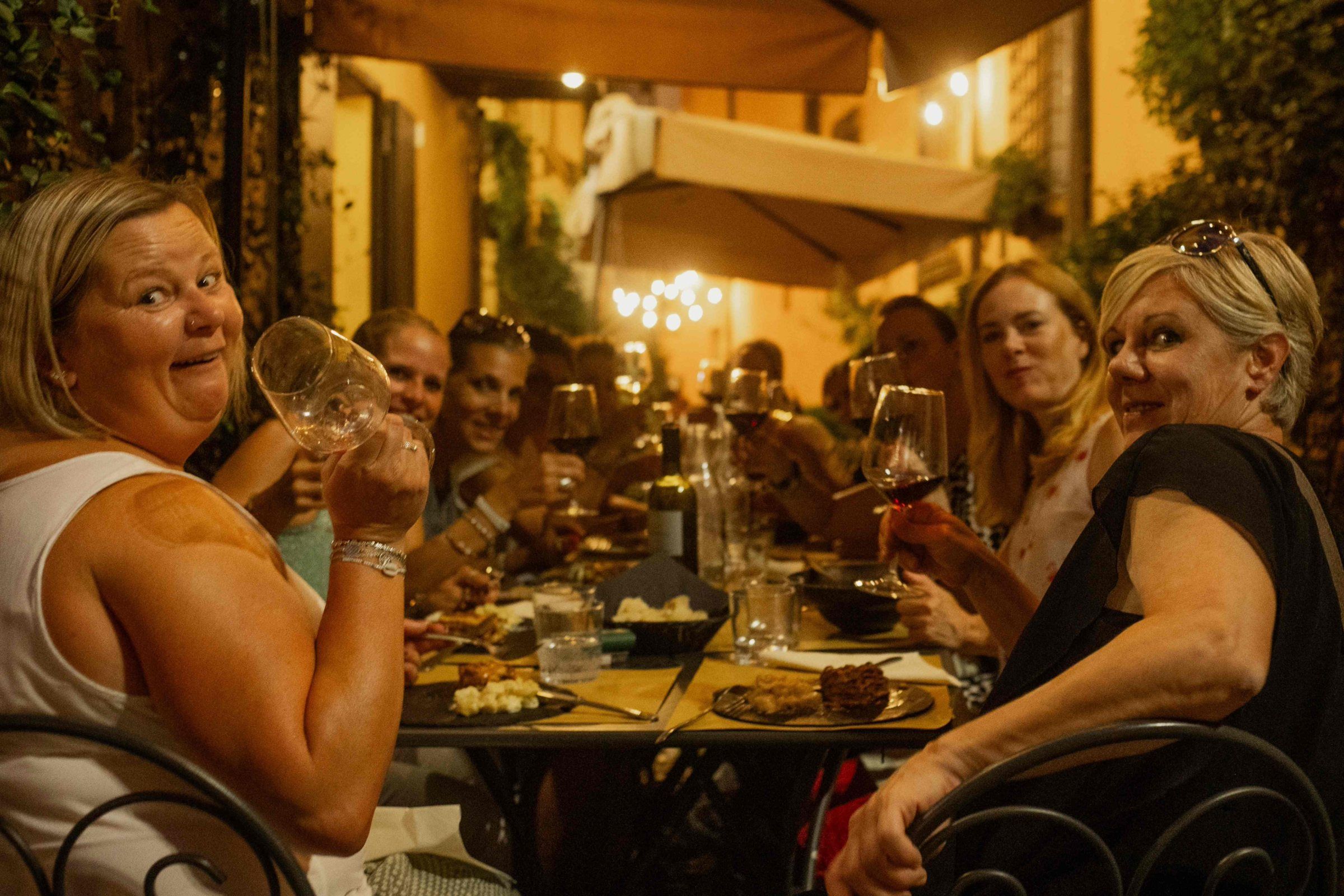 Guests raising their glasses at a long candlelit table in a Bologna courtyard