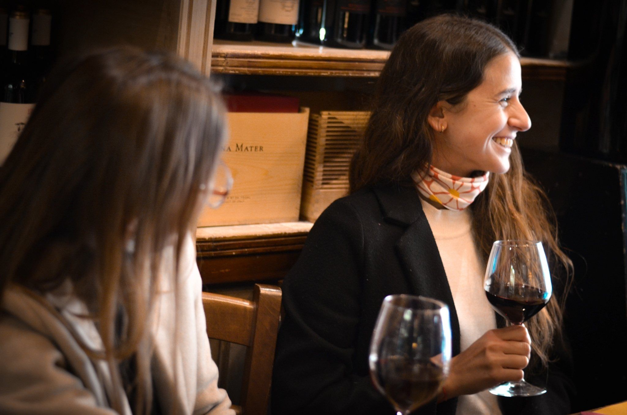 A guest smiling with a glass of red wine in a wine bar